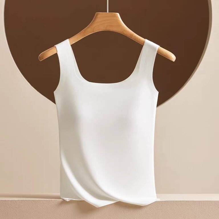 A white sleeveless top displayed on a wooden hanger against a muted background.