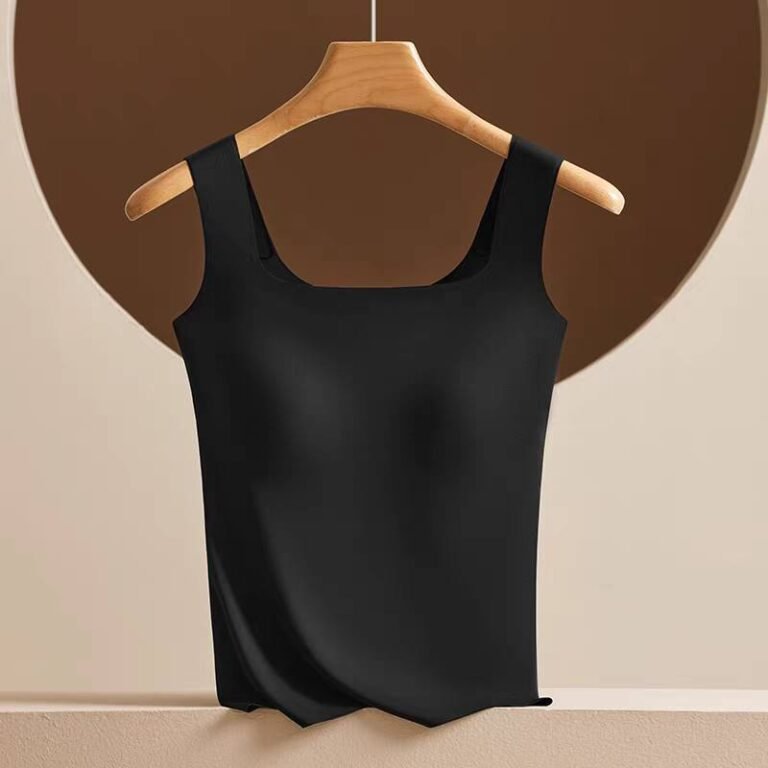 A black sleeveless top hanging on a wooden hanger against a neutral background featuring a circular shape.
