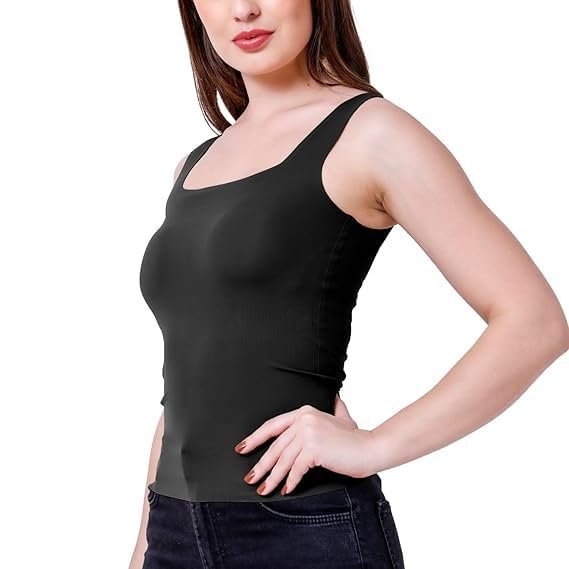 A woman posing in a black tank top and dark jeans.