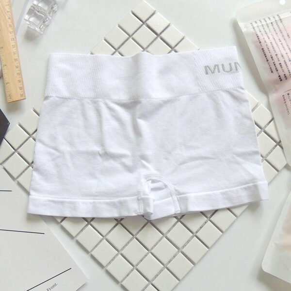 White Munafie shorts displayed on a tiled surface with a ruler and other items.